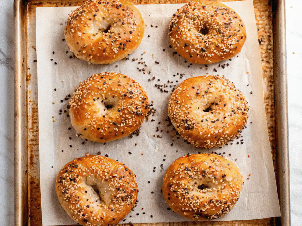 Freshly baked cottage cheese bagels on parchment-lined pan