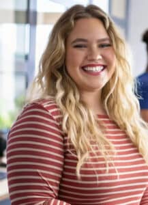 Emily Taylor – Founder of Quick Cake Recipes Emily Taylor, a smiling baker with long blonde hair, wearing a striped shirt, in a bright kitchen, representing Quick Cake Recipes.