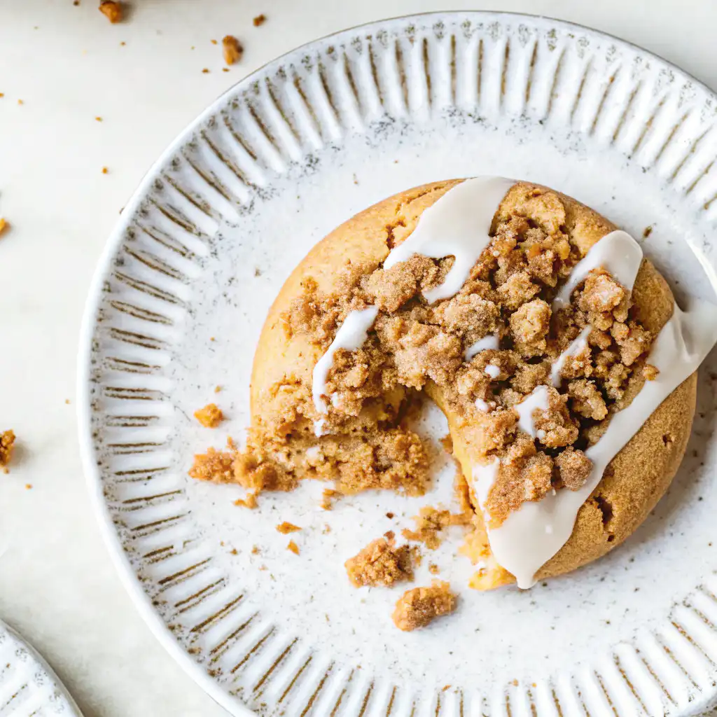 Coffee cake cookie with streusel and icing, bitten cookie on plate