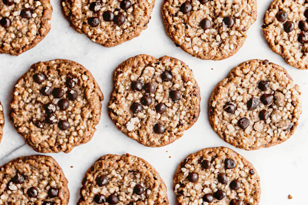 Freshly baked chewy oatmeal chocolate chip cookies with crispy edges, melty chocolate chips, and crunchy oats on a white background