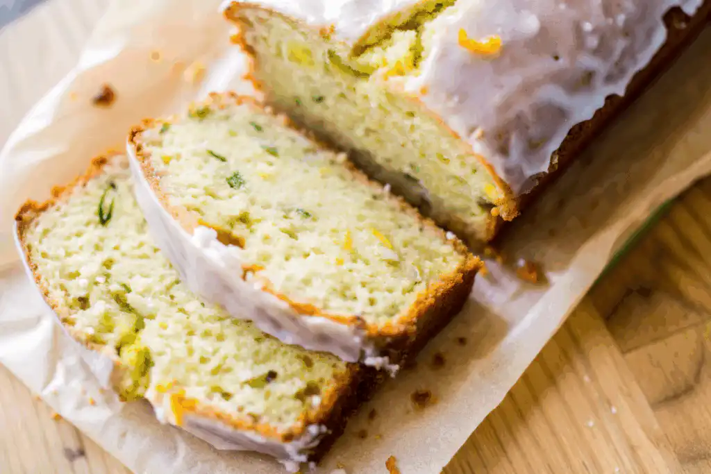 Close-up of sliced lemon zucchini bread showing moist crumb with zucchini flecks and glossy lemon glaze on top.