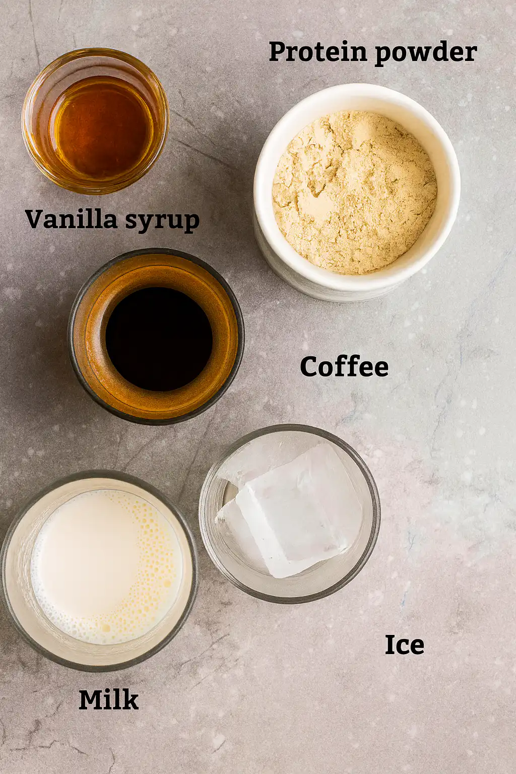 Ingredients for protein coffee recipe including protein powder, vanilla, milk, coffee, and ice
