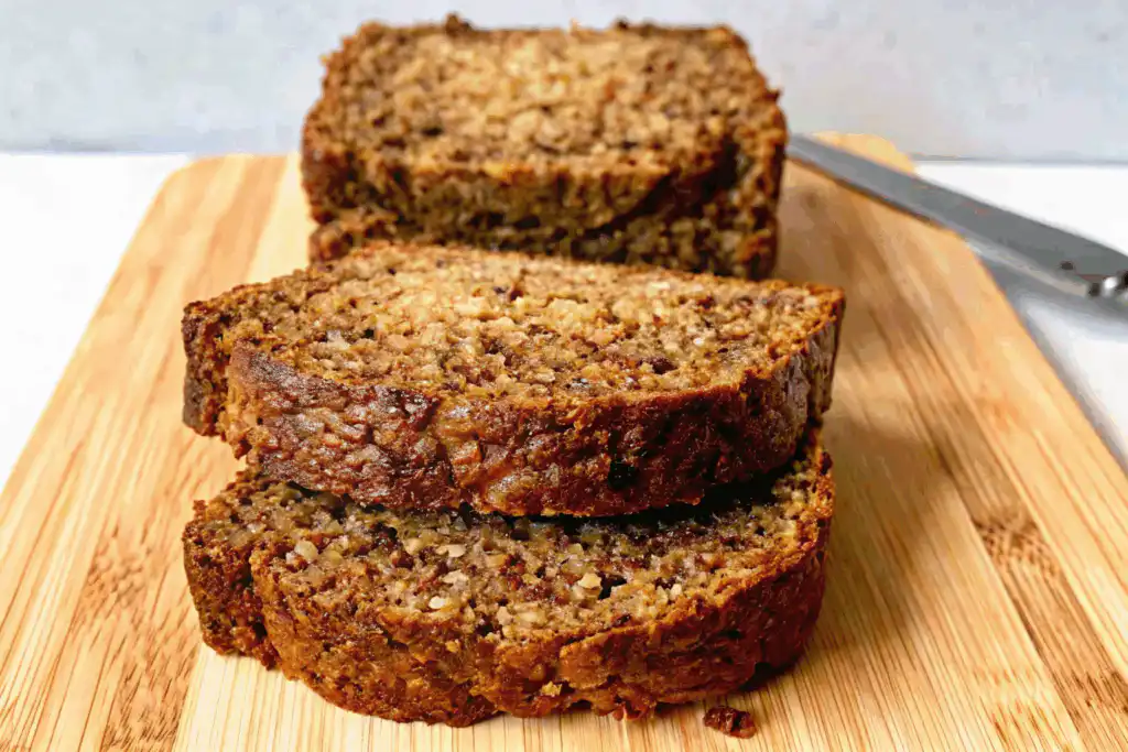 Moist zucchini bread slices on a wooden cutting board with a golden crust and fluffy texture.