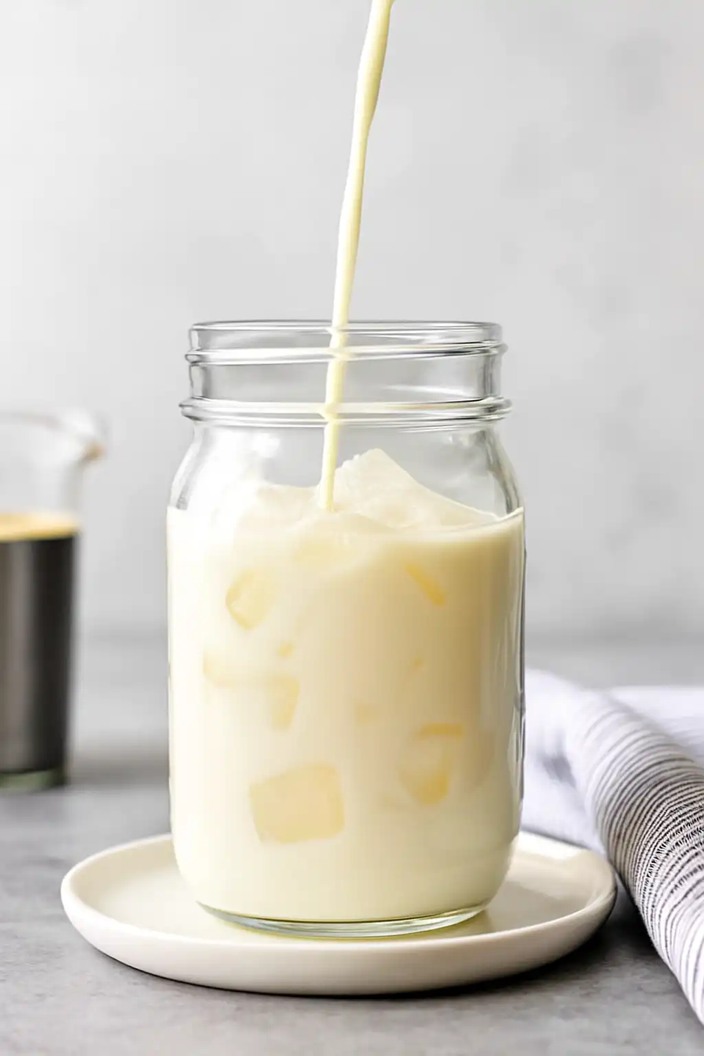 Pouring protein milk into glass with ice for protein coffee recipe