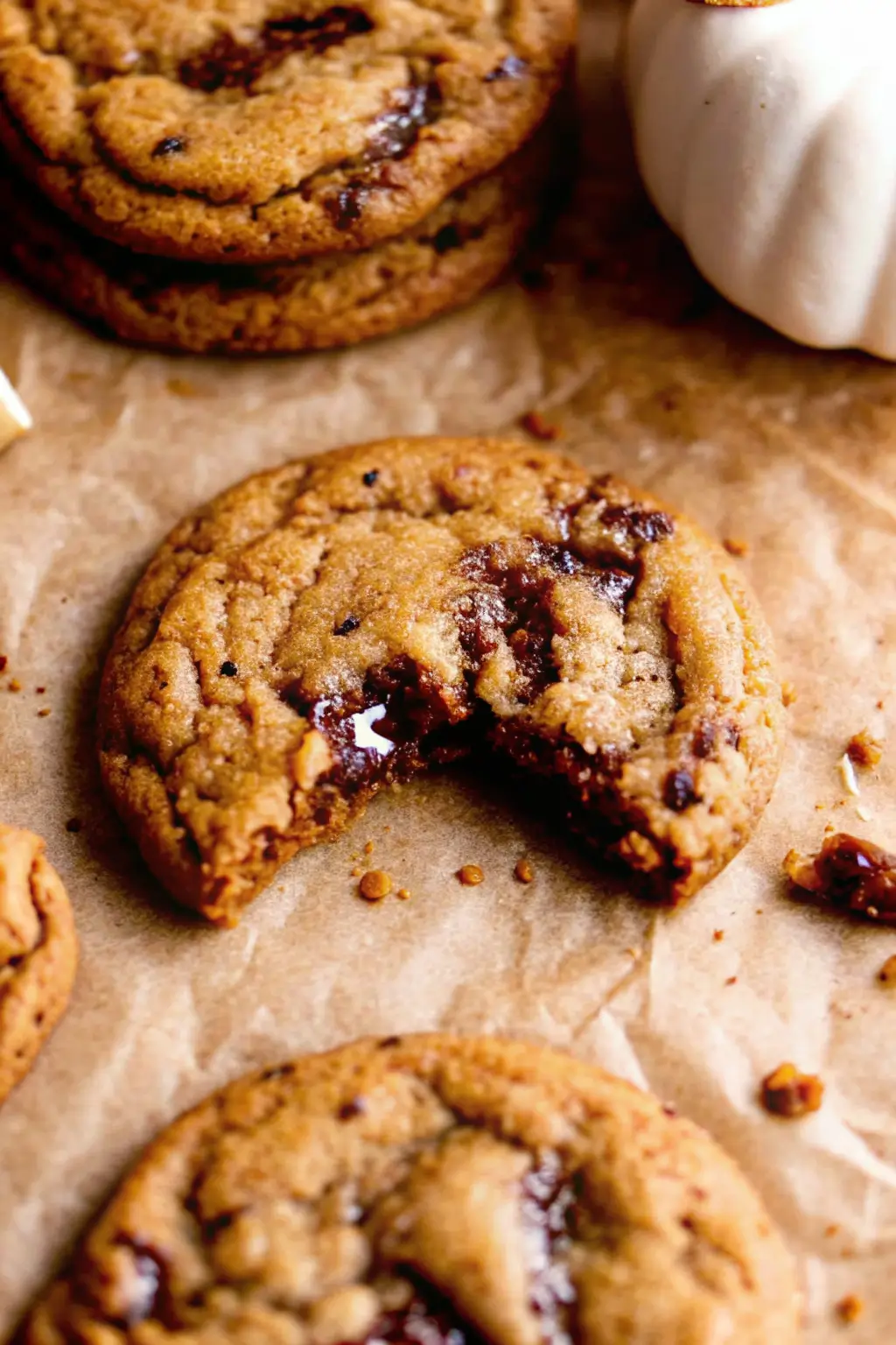 thick-chewy-pumpkin-chocolate-chip-cookies Chewy pumpkin chocolate chip cookie with melty chocolate center on parchment paper