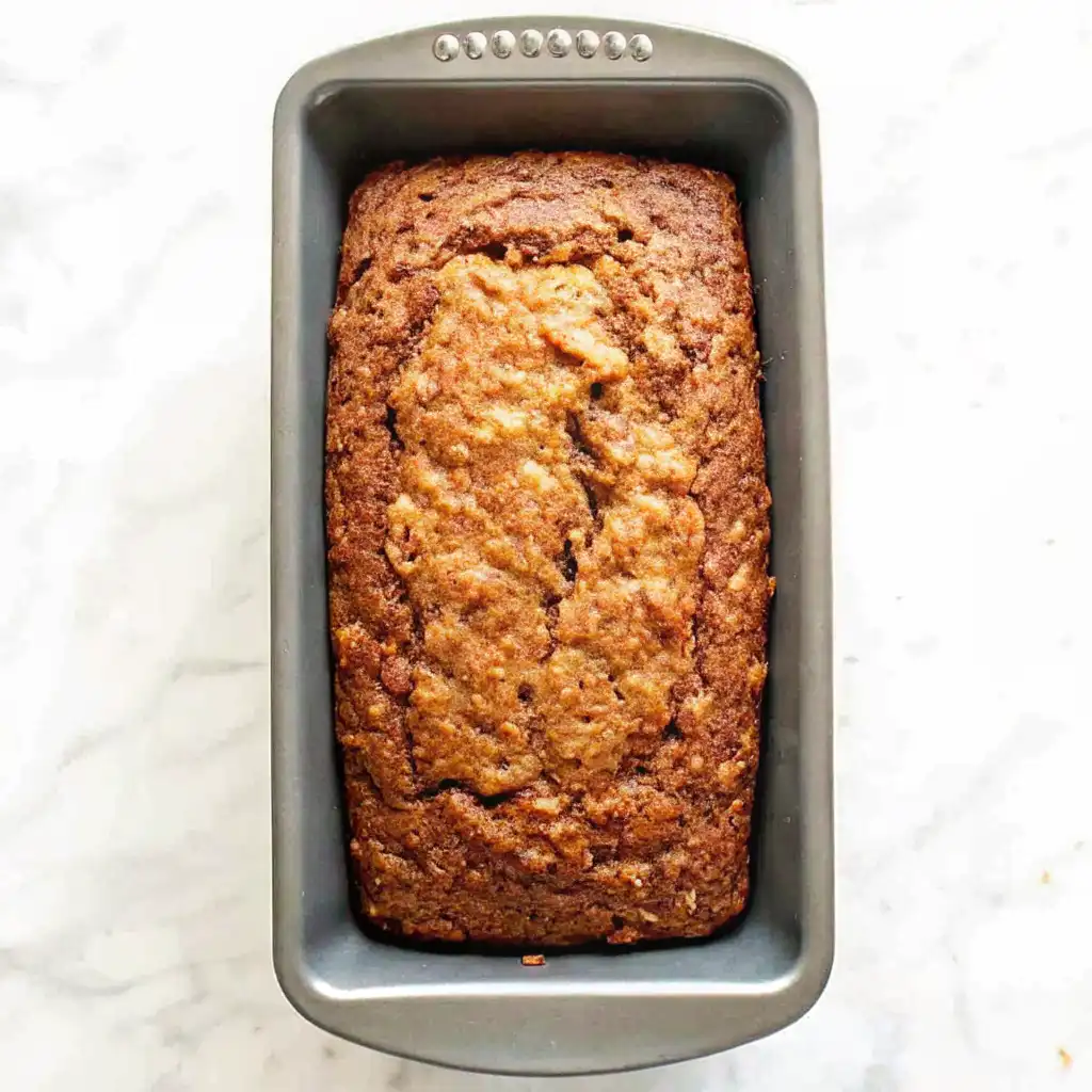 Freshly baked moist zucchini bread loaf in a pan with a golden-brown crust.