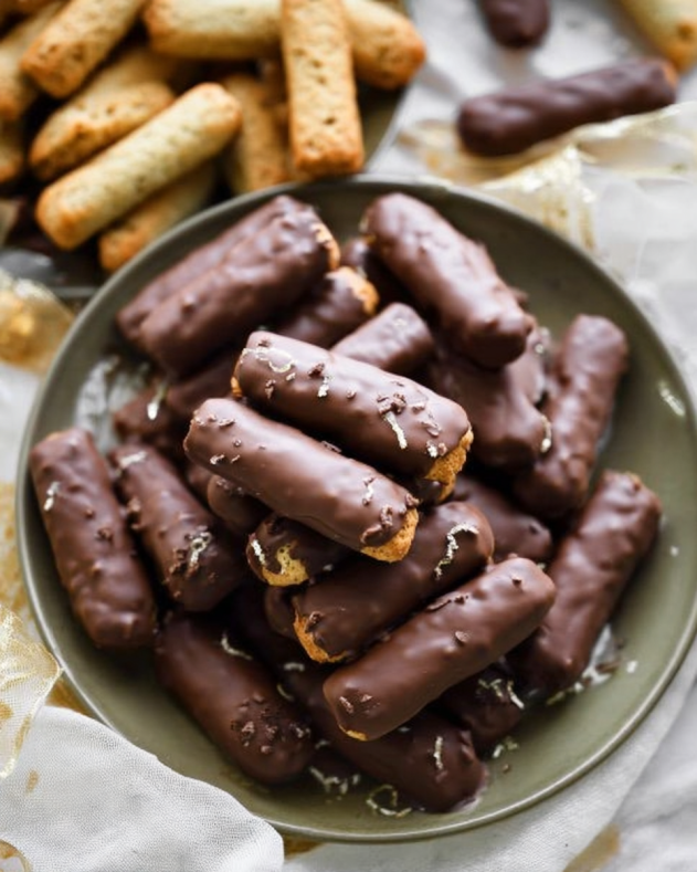Chocolate-Dipped Cigar Cookies: Crisp, golden cigar-shaped cookies coated in smooth dark chocolate, elegantly arranged for a classic look perfect for gifting or celebrations.​