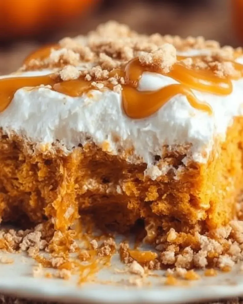 Delicious pumpkin poke cake topped with whipped cream and spices