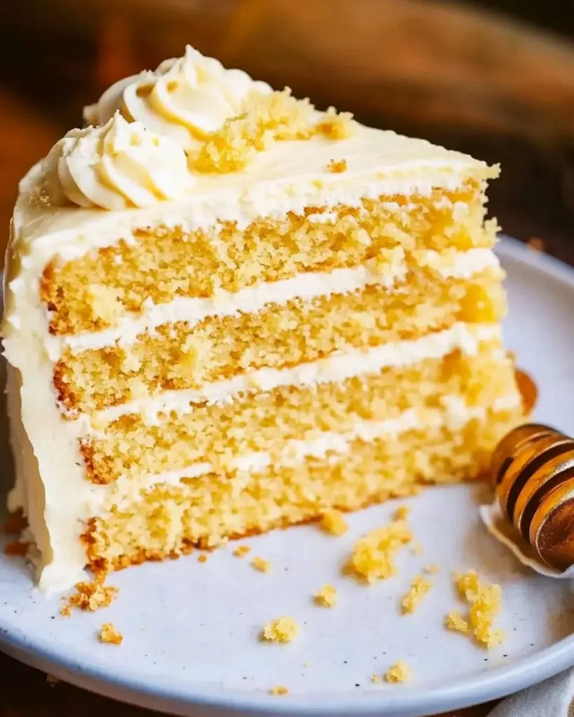 Cornbread cake with whipped honey buttercream frosting on a rustic plate