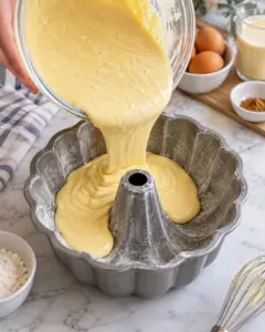 Eggnog cake batter pouring into a greased and floured Bundt pan