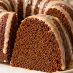 Close-up slice of glazed gingerbread Bundt cake showing moist dark crumb and ridged crust